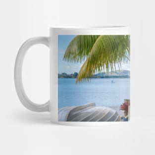 Tropical garden frames view over white clinker dinghy to bay with stand-up paddle-boarder in distance. Mug